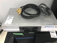 Photo showing the Panasonic DVD video recorder model DMR-E55 with three RCA cables on top.