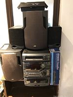 Front view of stacked JVC stereo components with Kenwood speakers arranged around and Sonicview satellite receiver box visible.