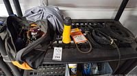 Overview of the lot showing the tool bag, yellow flashlight, various snow blower belts, and other tools arranged on a shelf.