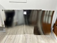 Three polished steel sheets standing upright, showing reflective, shiny surfaces with minimal marks.