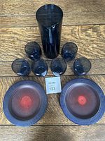 Overview of entire lot showing blue glass pitcher, six glasses, and two wooden plates on wood surface.