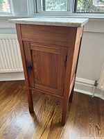 Full side view of the night stand showing the oak wood finish and door with metal latch.