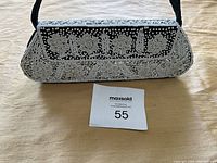 Front view of the rectangular black evening bag with intricate white bead floral patterns and snap closure.