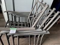 Four stacked dark grey metal patio chairs showing metal lattice seat and decorative backrests with circular detail.