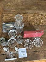 Overview photo showing two pewter candleholders, two clear glass Iittala candleholders, Riihimäen Lasi candleholders in original red box, clear glass water jug and small glass, box of small candles, and a single white candle.