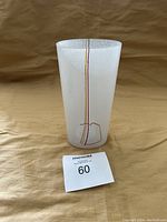 Front view of Kosta Boda frosted white glass vase showing the vertical rainbow lines and cylindrical shape.