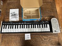 Full view showing flexible piano keyboard, portable speaker, instruction manual, original box and foam insert.
