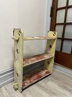 Full bookshelf standing upright against wall showing three shelves and side decorative cutouts