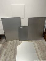 Four sheets of sheet aluminum leaning against a wall, showing size and overall condition