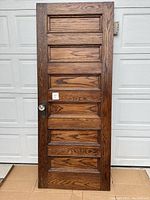 Front view of six panel wooden door showing full door and cut glass door knob on left side with metal backplate.