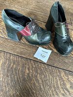 Pair of vintage women's platform shoes in green, black, and red leather on wooden floor, showing overall look and shape