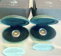 Two 2000 Polar Bear $2 Proof coins in green leather-like cases with certificates in front of original boxes.