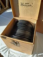 View of the open Amtill Platterpak chest showing a dense stack of 45 RPM vinyl records in paper sleeves.