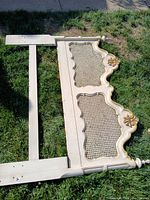 Close-up of partially disassembled decorative bed frame showing cane inset headboard with gold floral accents and damage.