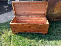 Open cedar wood blanket chest on grass showing interior and hinged lid