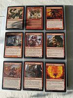 Close-up of nine Magic the Gathering cards in sleeves, showing red cards with creature and instant types, with detailed artwork and text.