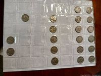 Multiple US nickels in a plastic coin holder arranged in rows, some showing the Buffalo nickel obverse.