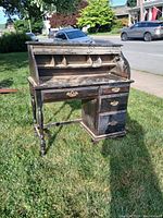 Front view of vintage wooden secretary desk with roll-top open showing compartments and drawers