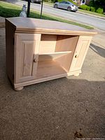 Photo of wooden TV stand showing front with two cabinet doors and open shelf