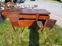 Front angle showing open drawers and cabinets, detailed brass hardware, wood grain, and surface wear.
