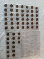 Top view of three plastic coin holders with 65 Wheat Pennies arranged in slots, with some empty slots.