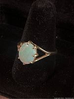Front view of a 14k gold ring with an oval white opal stone showing the prong setting and the ring's band design.