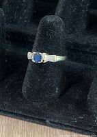 Photo of 14k gold ring with blue stone and diamond accents on black velvet background
