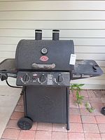Front view of the charcoal grill with control panel and side burner visible