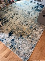 Full view of the area rug laid out in a living space showing size and color pattern.