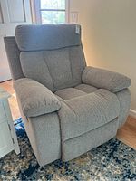 Front left view of gray reclining armchair showing padded seat, back and armrests