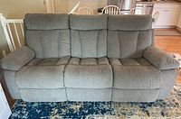 Front view showing the full gray fabric sofa with recessed armrests and plush back cushions.