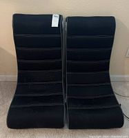 Two black fabric gaming chairs side by side, showing contoured backs and grey piping detail.