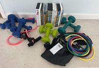 Wide shot showing all hand weights, resistance bands, carrying bag, and boxed exercise equipment.