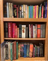 Books arranged on wooden bookshelf including Stephen King novels, classics, and reference books