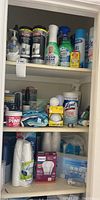 Three shelves filled with assorted kitchen cleaners, lightbulbs, disposable cups, and wipes.