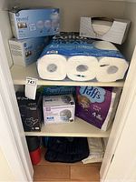 Shelf with GE Reveal 40W lightbulbs boxes, Cottonelle Ultra Clean toilet paper pack, Puffs tissues, Scott Paper Towels, and box of cotton pads.