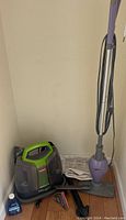 Wide shot of Shark steam mop and Bissell spot cleaner placed on floor with cleaning cloth