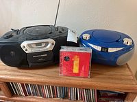 Photo showing Philips portable stereo, Magnavox CD player, and stack of CDs on wooden surface