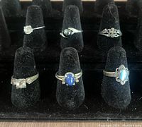 Six sterling silver rings displayed on black ring stand