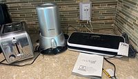 Overview of all items: Emerson wine chiller, NutriChef food sealer, and stainless steel toaster on kitchen counter.