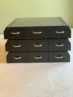 Closed view of the three black pod holders stacked, showing three drawers each with silver pull handles.