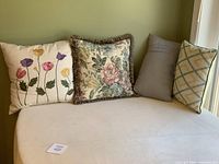 Four assorted throw pillows placed side by side on a beige surface.