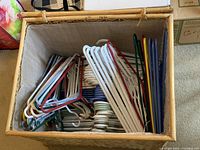 Top-down view of the woven basket filled with colorful plastic and metal wire hangers.