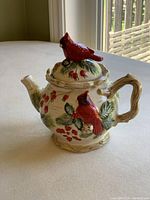 Side view showing handle, spout, and cardinal on lid