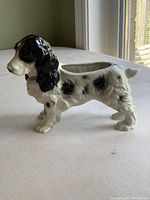 Left side view of porcelain Cocker Spaniel dog figurine planter showing black ears, black spots, open hollowed back, and standing pose.
