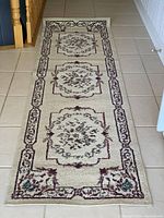 Full view of the hallway runner laid on tiled floor showing the three central floral medallions and border pattern.