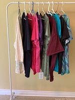 Photo showing 10 tops hanging on rack, various colors and styles visible