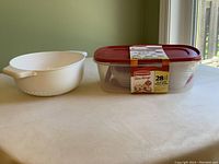Photo showing Rubbermaid 28 Piece Take Alongs food storage containers set with maroon lids, next to a white plastic strainer with handles.