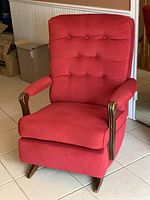 Front view showing red tufted rocking chair with wooden rockers and armrest supports.