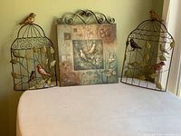 Overview photo showing the two metal birdcage wall hangings flanking the central bird-themed canvas artwork.